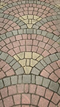 A top-down perspective captures the textured beauty of interlocking, multi-colored pavers laid out in an elegant, sweeping European fan pattern. Video transition, 4k, 60 fps