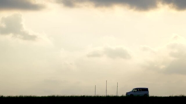 夕日を背景に連なって走る車のシルエット
