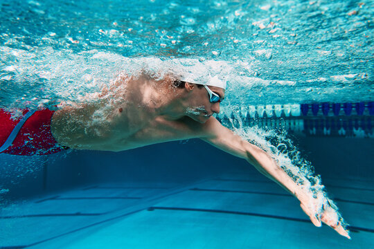 Close up of swimmer performing freestyle underwater. Concept of swimming technique, sports science, hydrodynamics, athlete training, and aquatic performance.