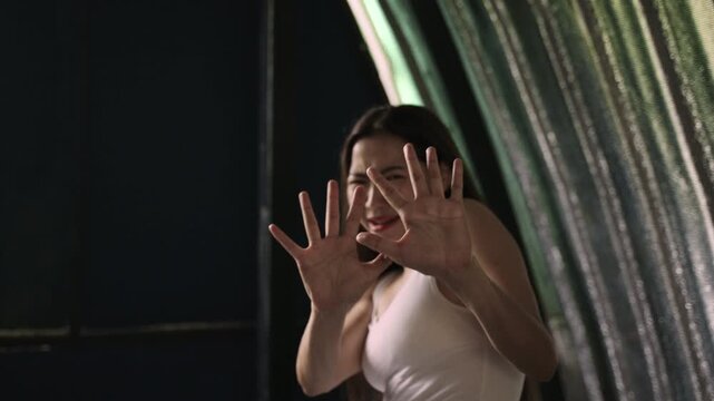 Unhappy and frightened Asian young woman hands raised in fear to stop violence and prevention from rights violations with worried sadness and depression stress in her room at home. Violent concept. 