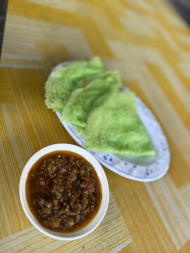 Malaysian Green Pandan Crepe Pancake Lempeng with Spicy Chilli Sambal Sauce Dip on Table Background