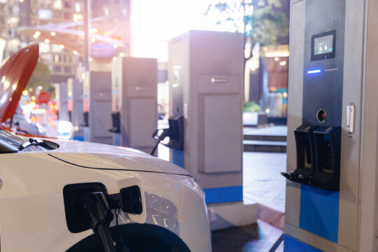 Electric car vehicle plugged into Fast charger charging station at curbside.