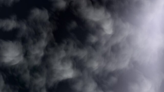 Grey thick billowing clouds in dark night sky with soft hazy white atmospheric smoke. Suitable for background, texture or dramatic scenes.