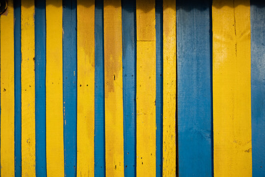 Painted wooden planks creating a blue and yellow textured backdrop