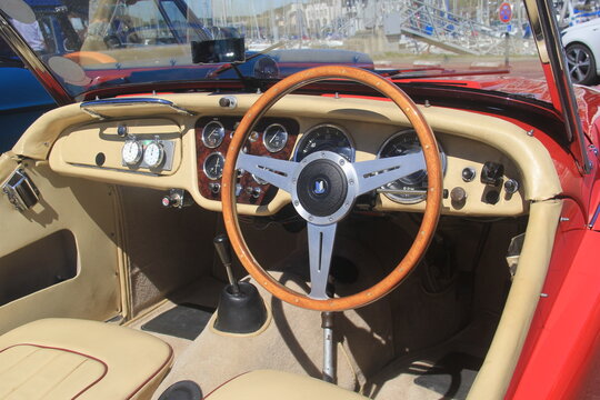 BINIC, FRANCE - JUIN 7, 2026 : Plan large sur l'int&eacute;rieur et le tableau de bord d'une voiture de sport classique britannique Triumph TR3, avec volant de collection en bois &agrave; trois branches.