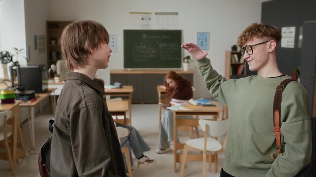 Two silly teenage students pulling pranks on each other before class, standing in modern 3D modelling class