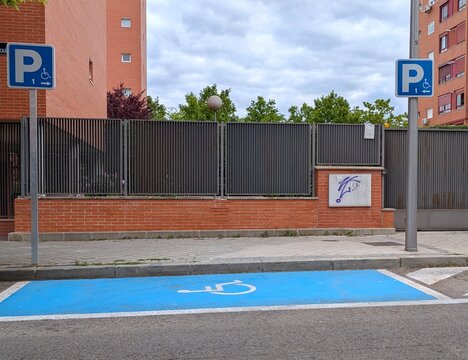 Espacio reservado para veh&iacute;culos con conductores discapacitados, con el s&iacute;mbolo blanco de un hombre en silla de ruedas en el suelo pintado de azul, en una calle de Madrid	