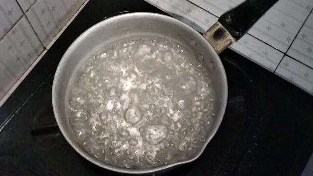 Boiling water in a metal saucepan on a kitchen stove