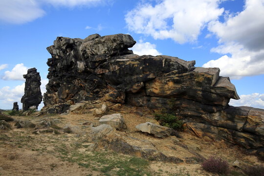 Imposante Sandsteinfelsen der Teufelsmauer im Harz. Eine markante Felsformation mit einer freistehenden Felsnadel vor blauem Sommerhimmel mit wei&szlig;en Wolken. Ideal als Naturbild.