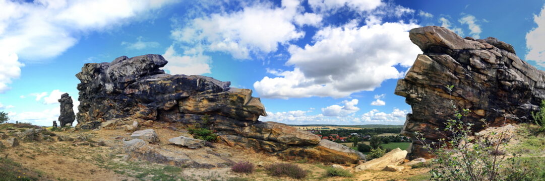 Imposante Sandsteinfelsen der Teufelsmauer im Harz. Eine markante Felsformation mit einer freistehenden Felsnadel vor blauem Sommerhimmel mit wei&szlig;en Wolken. Ideal als Naturbild.