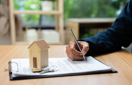 Real estate contract signing and home purchase concept with house model, keys, and legal documents, representing property ownership, mortgage approval, home financing, and real estate transactions.