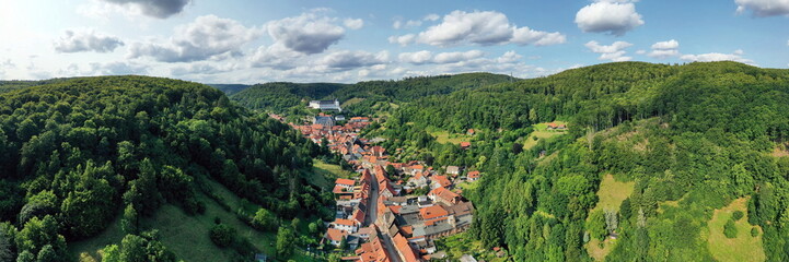 Fototapeta premium Malerische Luftaufnahme von Stolberg im Harz mit historischen Fachwerkhäusern, eingebettet in die grüne Berglandschaft mit Blick auf das Schloss. Perfekt für Tourismus und Reisen.