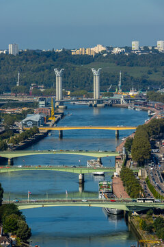 Scenic aerial view of Rouen bridges spanning the Seine River, featuring the modern Gustave Flaubert lift bridge against a cityscape backdrop in Normandy, France.