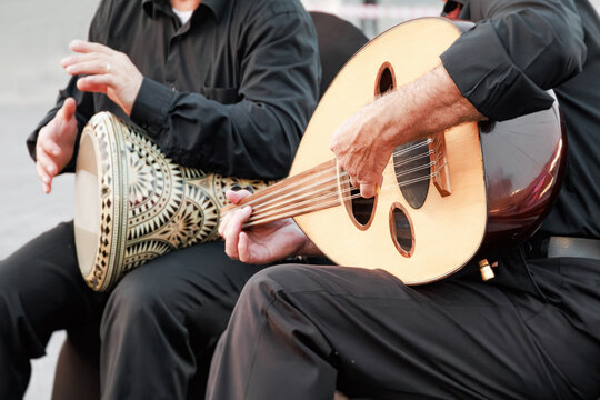 Two musicians performing Middle Eastern music with a wooden oud and an ornate percussion instrument, sharing cultural heritage