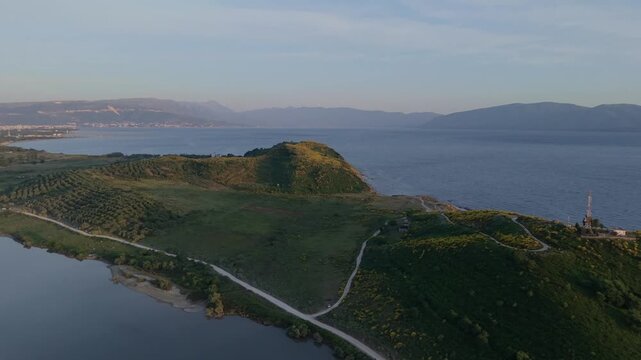 Aerial view of the lush green hills and coastal landscape of Vjose-Narte Delta Protected Area near the sea in Zvernec, Vlore County, Albania.
