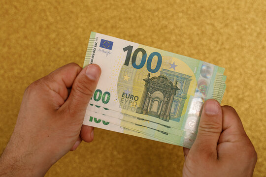 Close up of hands holding a stack of 100 Euro currency notes
