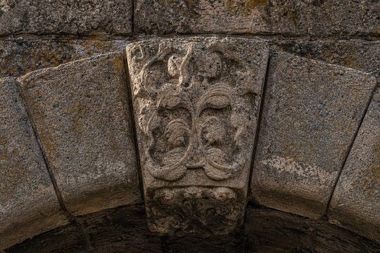 Ancient stone arch bridge keystone with intricate weathered carvings.