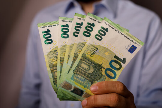 Close up of a man holding a fan of five 100 euro notes