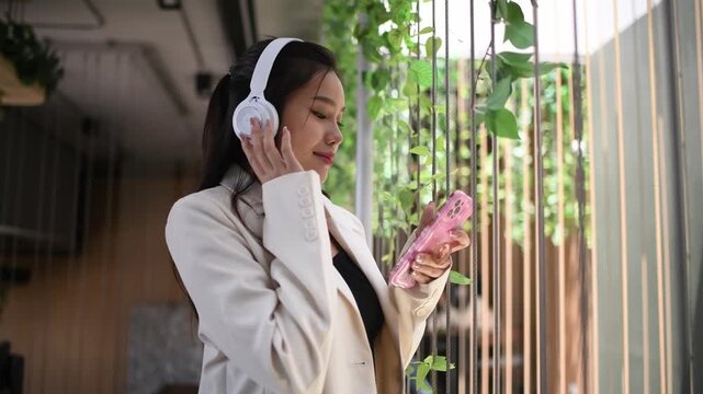 Businesswoman sitting indoor space wearing headphones while writing notes focused and productive work in a relaxed environment concepts of business education productivity and online learning.