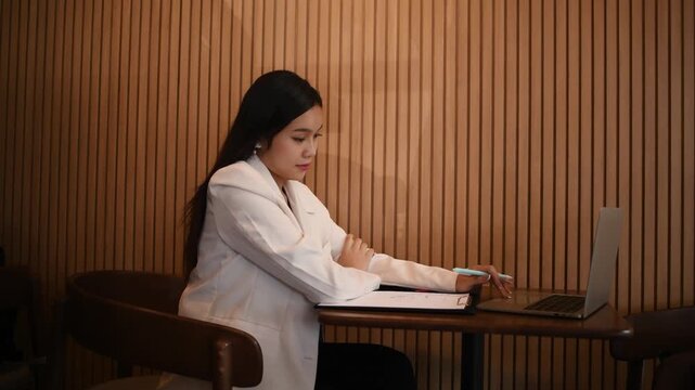 Woman working writing notes in notebook while using a laptop represents business education and professional development concepts of remote work studying and productivity.