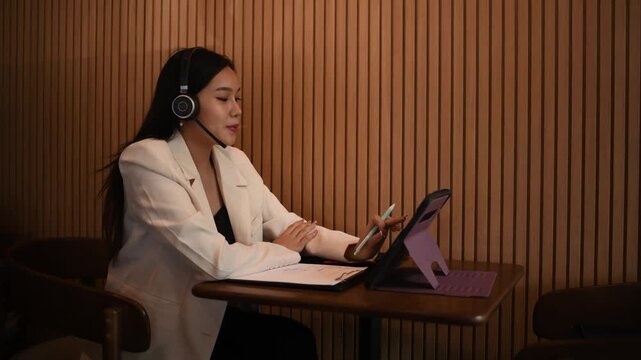 Businesswoman sitting indoor space wearing headphones while writing notes focused and productive work in a relaxed environment concepts of business education productivity and online learning.