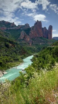 Mallos de Riglos, located in Spain, are towering sandstone formations characterized by their striking vertical shapes and reddish-brown hue. These geological features rise dramatically 