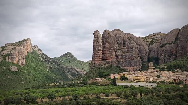 Aguero village in Spain is surrounded by the impressive rock formations known as "Mallos de Aguero." Nestled at the base of these towering, rugged cliffs, the village features traditional stone houses