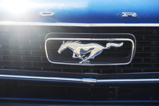 BINIC, FRANCE - JUIN 7, 2026 : Gros plan sur le logo embl&eacute;matique du mustang au galop sur la calandre chrom&eacute;e d'une voiture de collection Ford Mustang de couleur bleue.