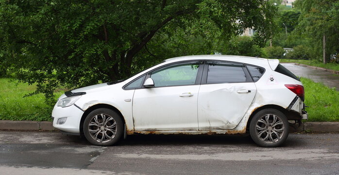 An old, dented white car is parked in the courtyard, Iskrovsky Prospekt, Saint Petersburg, Russia, June 18, 2026