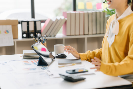 Digital Workspace: A focused individual is engrossed in a digital tablet, surrounded by documents, calculator, and office supplies, suggesting a modern approach to work and study.