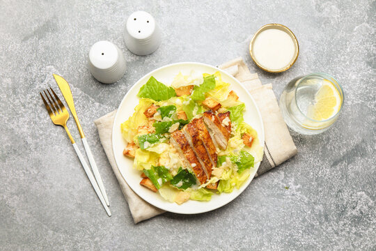 Delicious Caesar salad with chicken served on grey table, flat lay