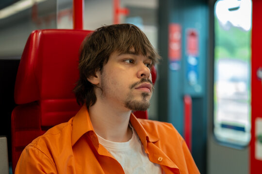 Young man travels by train and looks toward the window.