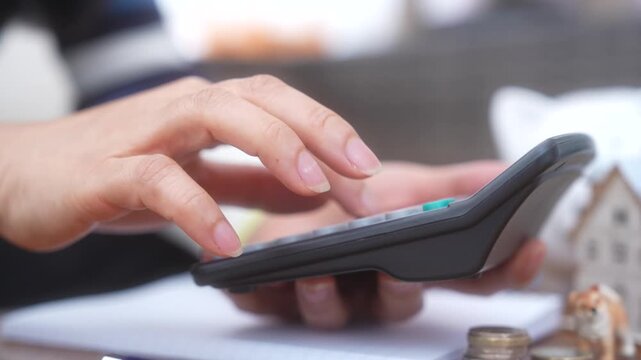 Closeup person calculating household expenses using calculator while managing personal finances. Financial planning, Budgeting, Savings, Mortgage calculation, Investment, Money management