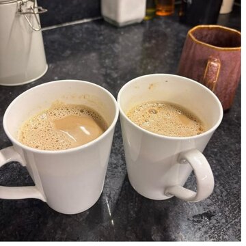 Two cups of milk tea on dark kitchen countertop