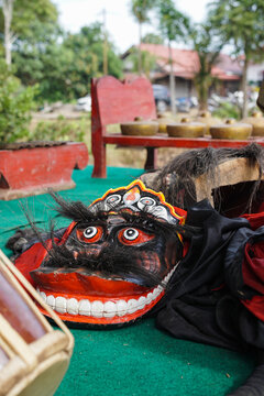 Traditional Indonesian Barongan mask resting beside gamelan instruments on a performance stage, representing Javanese cultural heritage and traditional arts