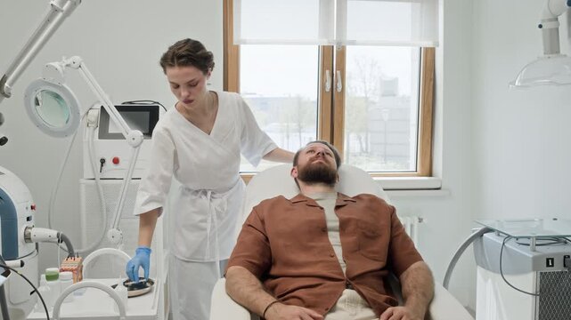 Caucasian cosmetologist preparing syringe for injection on middle aged Caucasian man in clinic. Video ideal for promoting male grooming and aesthetic medicine services