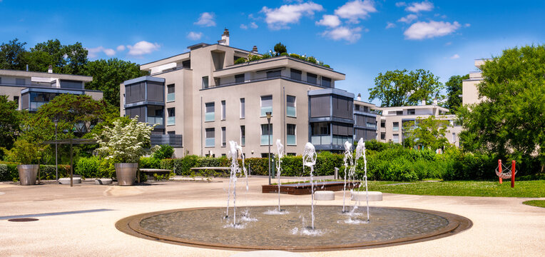 Immeuble r&eacute;sidentiel moderne haut de gamme bordant la fontaine du Pregny Parc sous un ciel d'&eacute;t&eacute;