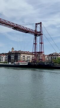 Vizcaya Bridge, a transporter bridge in Portugalete, Spain, is showcased with its striking red iron structure and intricate cable system. 