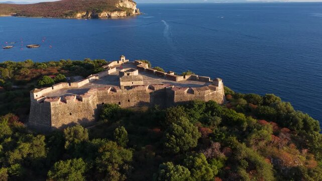 Aerial view of the triangular Porto Palermo Castle surrounded by lush green trees and the deep blue waters of the Ionian Sea in Porto Palermo, Qarku i Vlores, Albania.