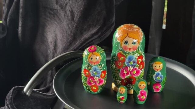 Russian Nesting Dolls in Green: A charming set of hand-painted Russian nesting dolls, adorned in vibrant green with floral motifs, are displayed on a dark surface.
