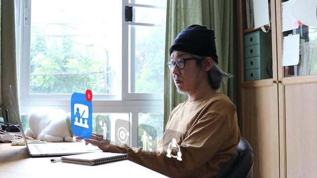 Mature East Asian man with glasses typing on laptop with white cat nearby, showing 3D tracked virtual classroom badge, target dartboard, and network link pop ups.