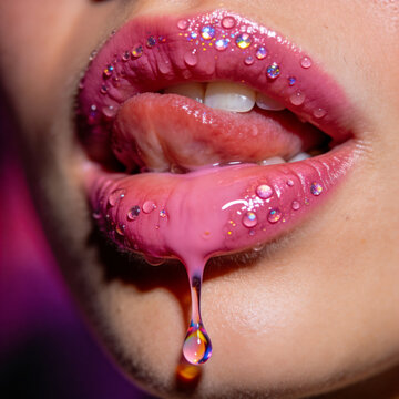 Close-up of glossy pink lips adorned with glitter and water droplets, a drop falling