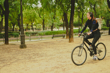 Fototapeta premium young woman riding a bicycle through the park in autumn 