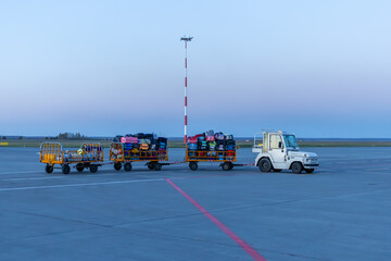 Naklejka premium Tow truck pulling baggage carts at morning airport