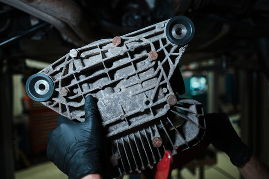 An Automotive differential housing, drive train component inspection, mechanic holding vehicle transmission assembly. Car and garage parts.