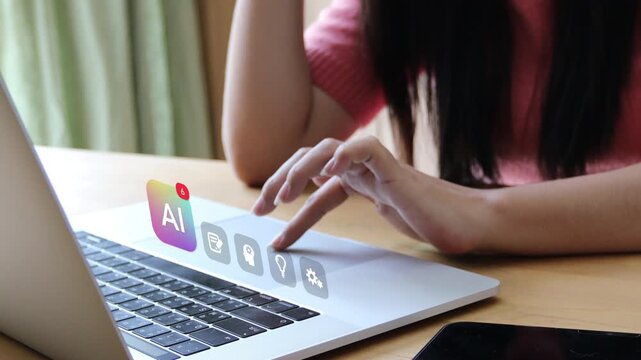 Close up of an adult Asian woman typing on laptop keyboard, showing 3D tracked virtual artificial intelligence assistant badge and creative brain pop up icons.