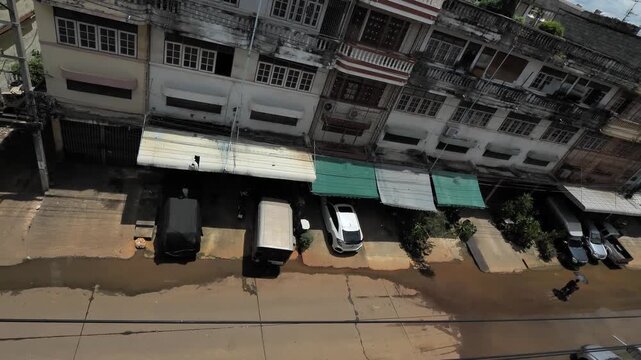 Urban street with parked car and row of aged residential buildings under cloudy sky
