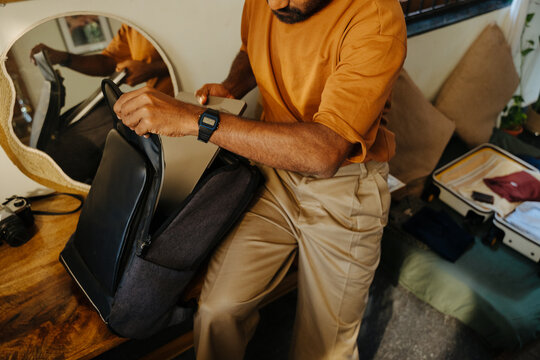 Man Packing Laptop into Backpack for Travel