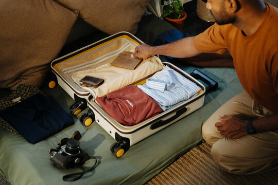 Man Packing Wallet into Suitcase Before Travel