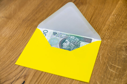 Polish banknotes in yellow envelope on wooden background
